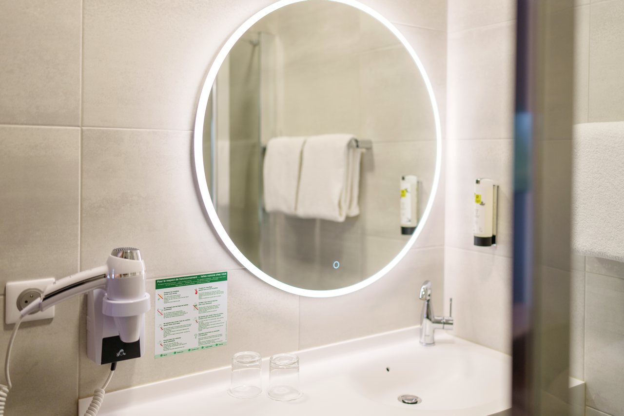 Vasque et miroir lumineux dans une salle de bain rénovée